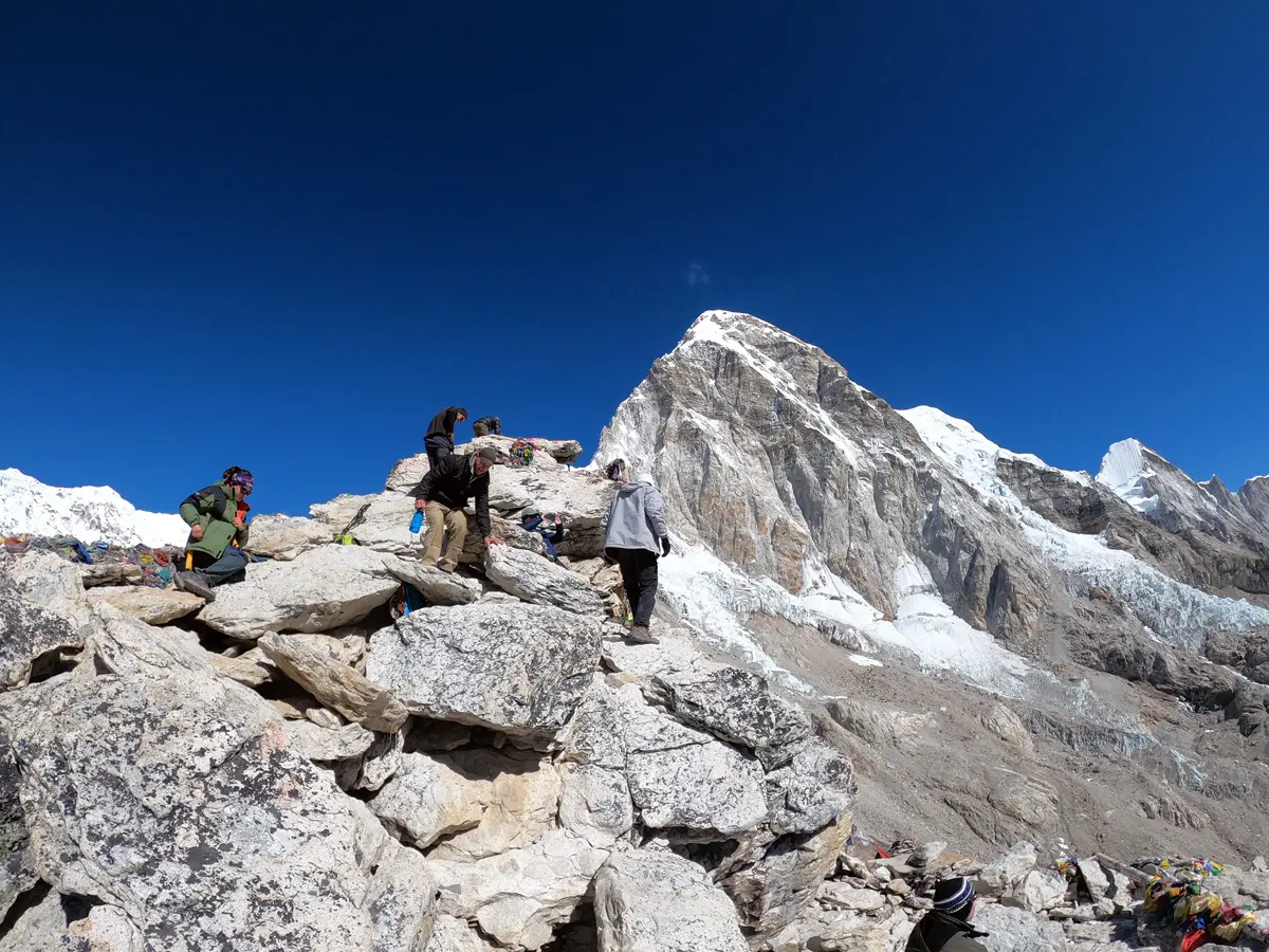 Trekkers navigating rocky terrain near Kala Patthar with snowy peaks in the background