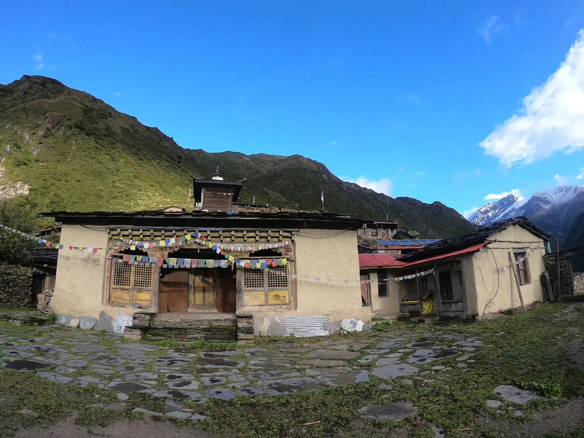Traditional Buddhist monastery surrounded by green hills and snow-capped peaks in Tsum Valley, Nepal