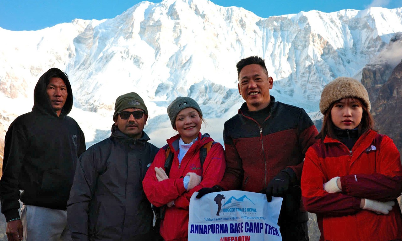 trekkers holding rugged trails nepal banner at the annapurna base camp