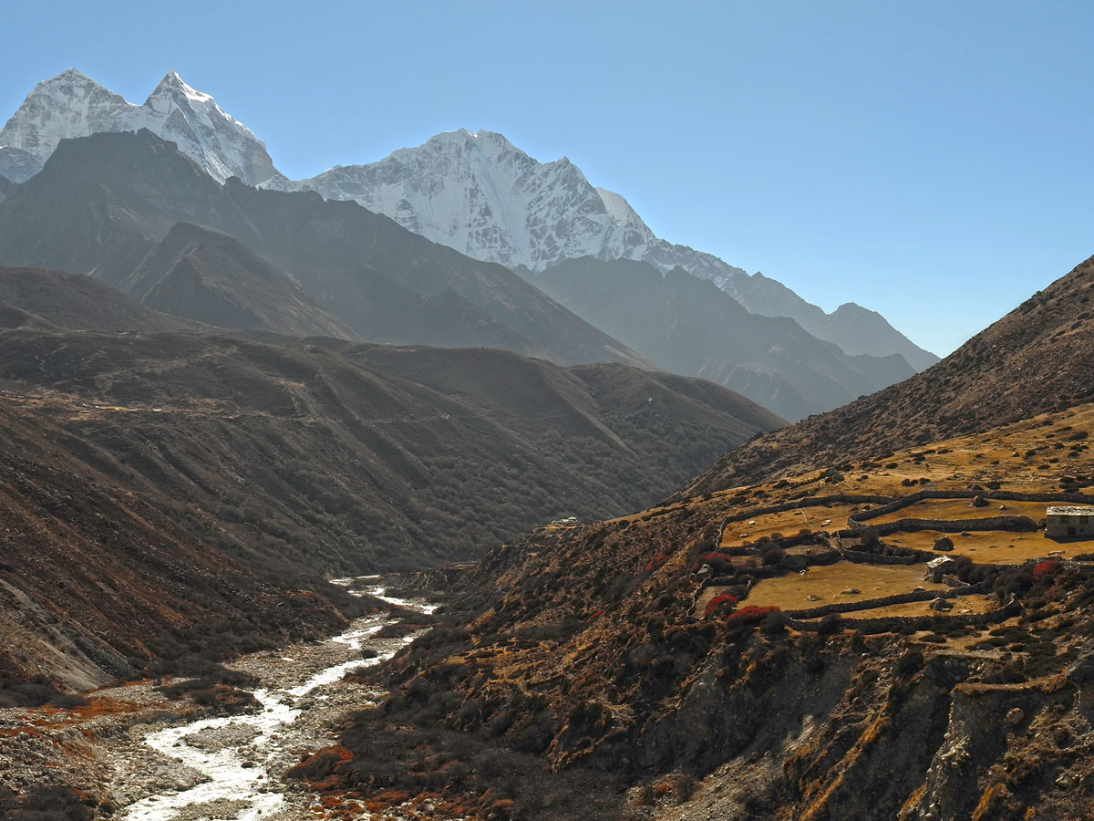 Glacial river winding through a rugged mountain valley in the Khumbu region under towering snow-capped Himalayan peaks