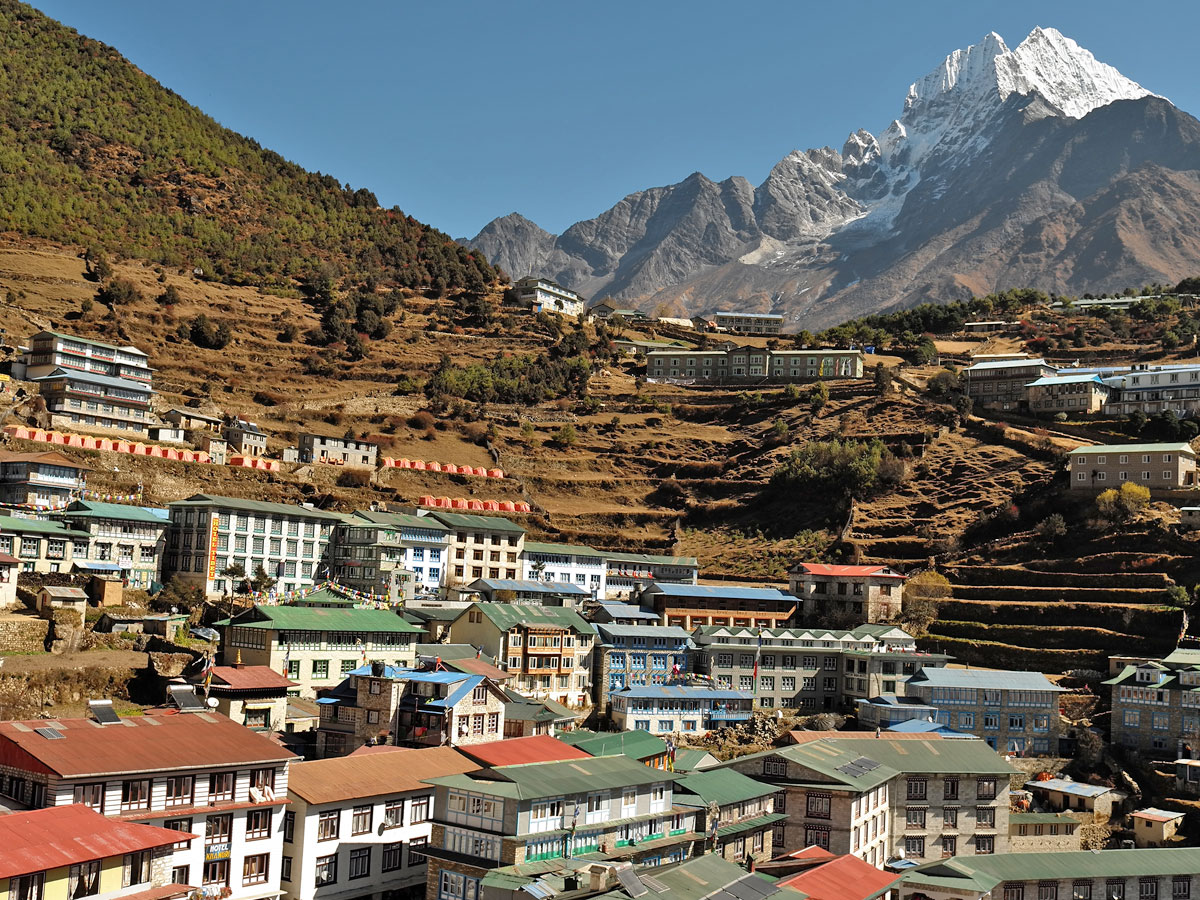 Amphitheater-shaped Sherpa town of Namche Bazaar with terraced hillsides, colorful lodges, and snow-capped mountain peaks