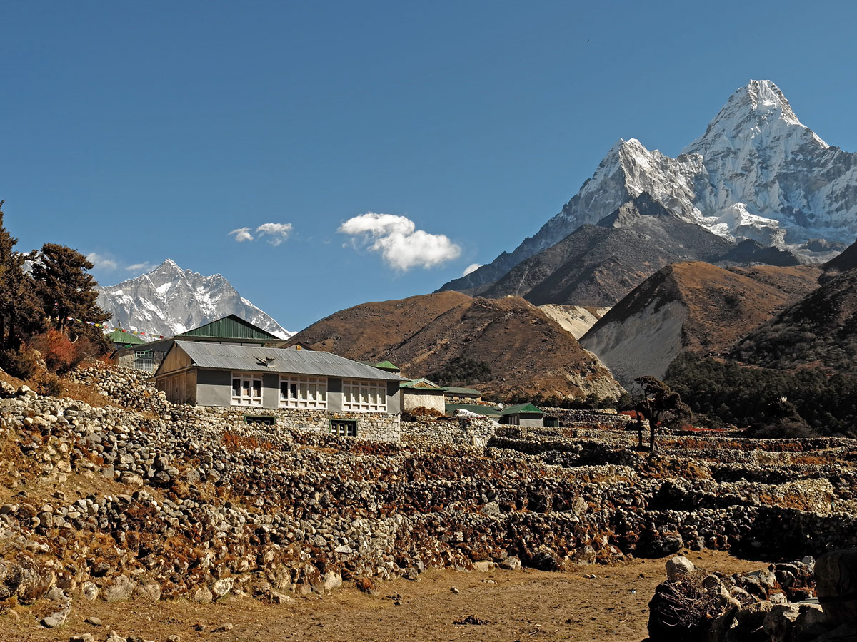 Stone-walled fields and mountain lodges in Pangboche village set against the backdrop of the iconic peak of Ama Dablam