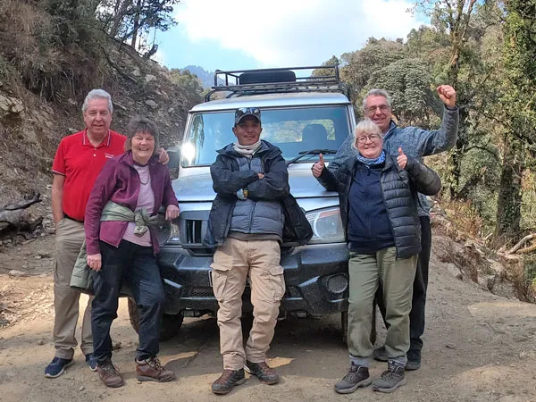 Group of trekkers and local guide posing in front of a 4WD Jeep during the Ghorepani Poon Hill drive and trek