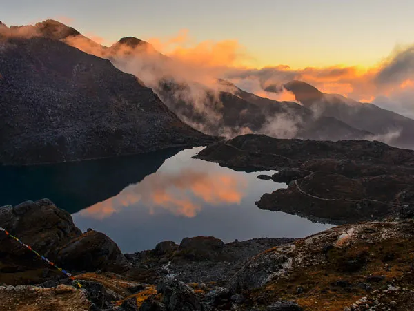 Golden sunset sky and low clouds reflecting over the tranquil waters of Gosaikunda Lake along the Langtang Gosaikunda Trek in Nepal