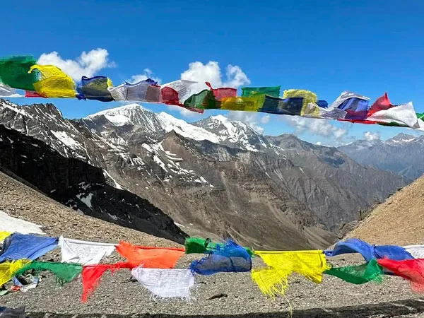 Colorful Buddhist prayer flags fluttering in front of snow-capped mountain peaks along the Lower Dolpo Trek in Nepal