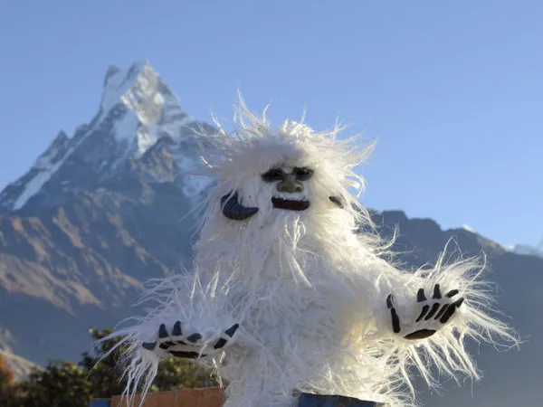 A playful Yeti figure posed against the backdrop of Mount Machhapuchhre (Fishtail) during the Mardi Himal Trek in Nepal.