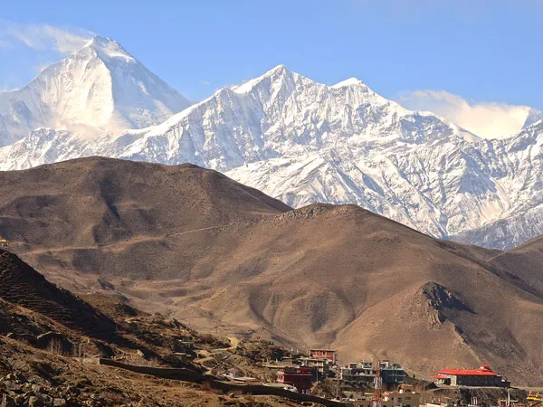 A panoramic view of the settlement below Muktinath set against the snow-capped Dhaulagiri mountain range during a Muktinath Darshan pilgrimage tour