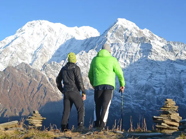 Two trekkers standing on a ridge looking at snow-covered Annapurna Himalayan peaks during the Short 3 Days Mardi Himal Trek in Nepal.