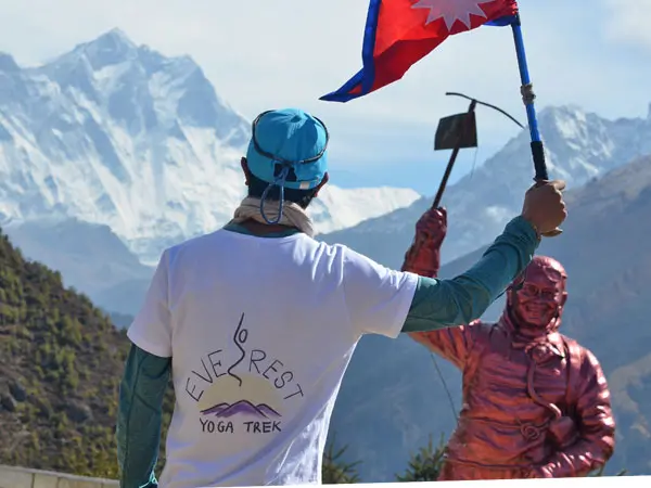 Trekker holding Nepal flag facing Mount Everest.