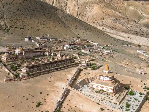 High-angle aerial view of ancient Buddhist stupas and a monastery complex in the arid landscape of Dolpo, Nepal.