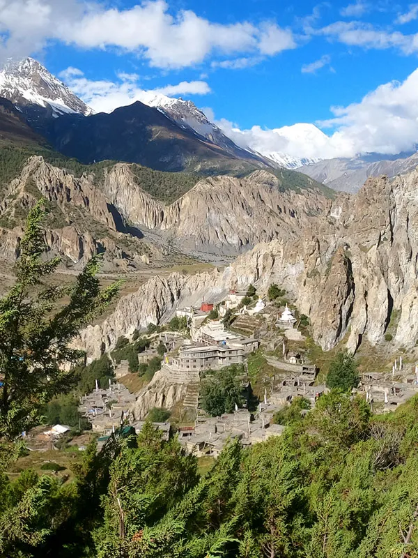 Panoramic view of the historic Braka Monastery nestled against dramatic, eroded rock cliffs in Manang valley on the Tilicho Annapurna Circuit Trek