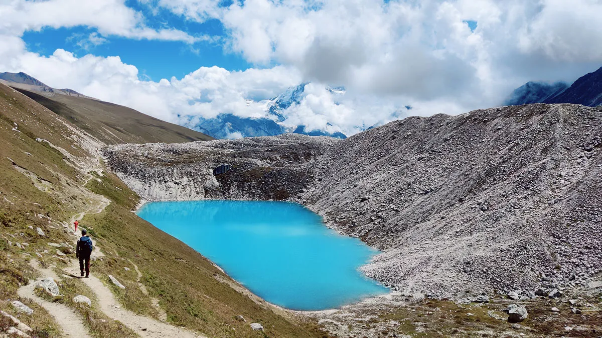 trekker walking next to the blue lake in manaslu circuit trek